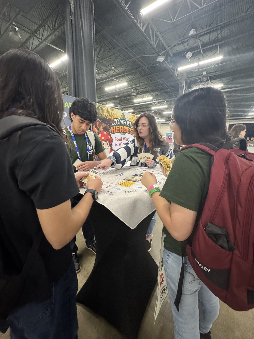 Young people playing the Compost Heroes card game together at EarthX 2026 in Dallas